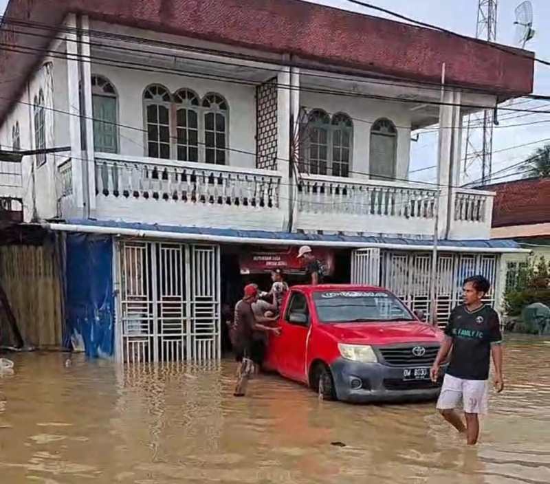 Banjir Sebatik. Genangan air merendam area pertokoan di Jalan Ahmad Yani, Pulau Sebatik, Rabu (12/11/2025). Warga tampak berupaya menyelamatkan barang dagangan dari banjir yang belum surut.